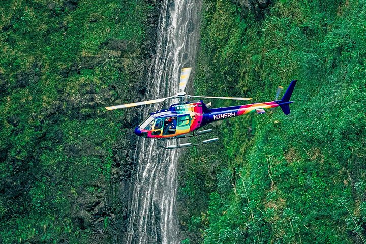 Colorful helicopter flying beside waterfall