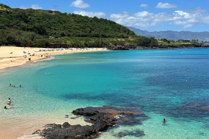 Curved sandy beach with turquoise water and green hills