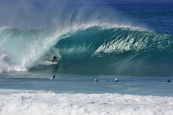 Large breaking wave with surfers paddling
