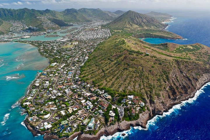 Aerial view of a coastal town below green hillsides