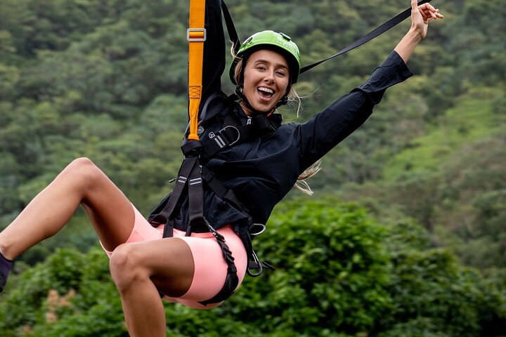 Woman ziplining over forested landscape